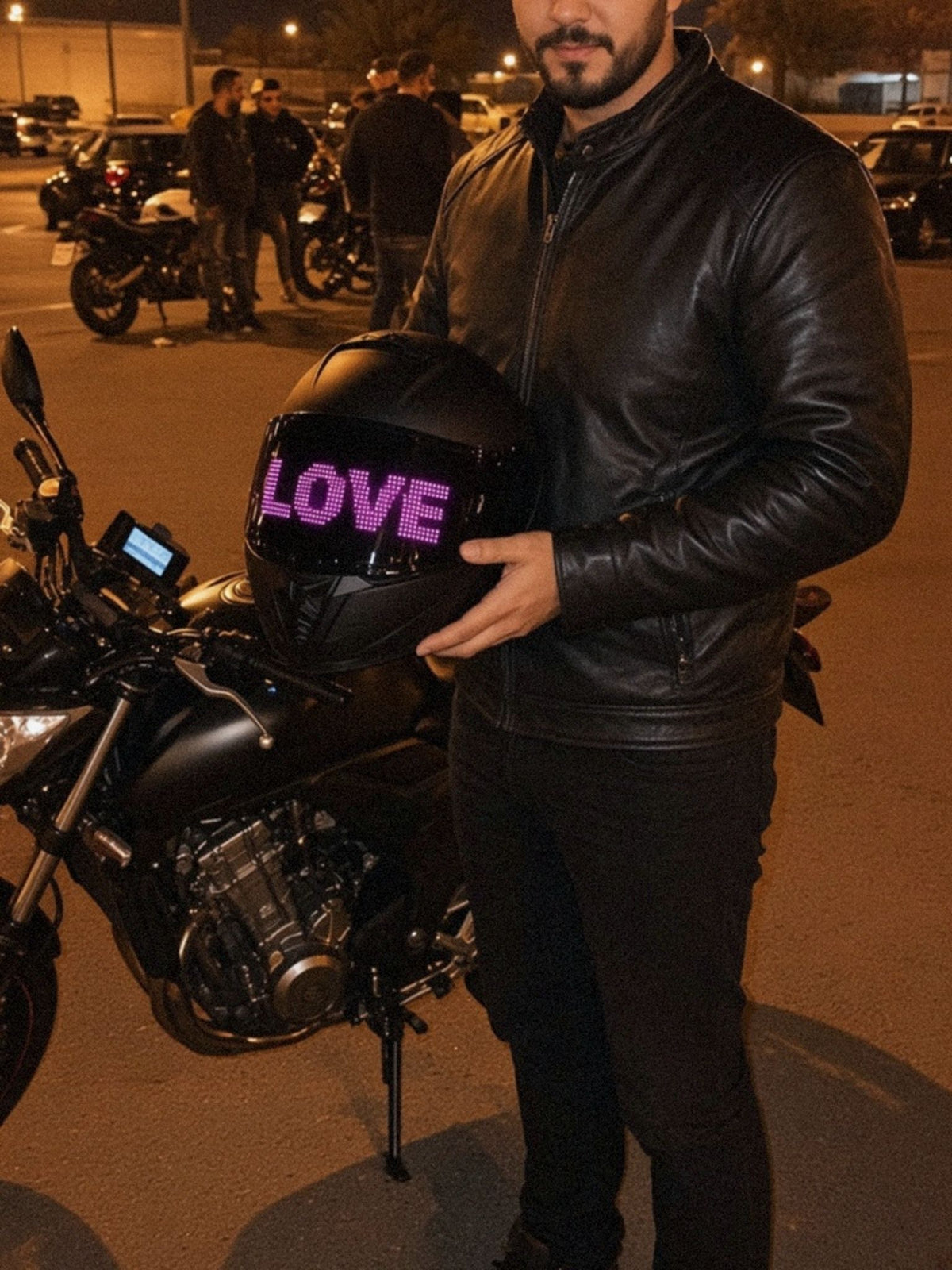 Motorrijder staat 's avonds op een meeting naast zijn geparkeerde motor en houdt zijn helm vast, het LED-vizierscherm toont LOVE